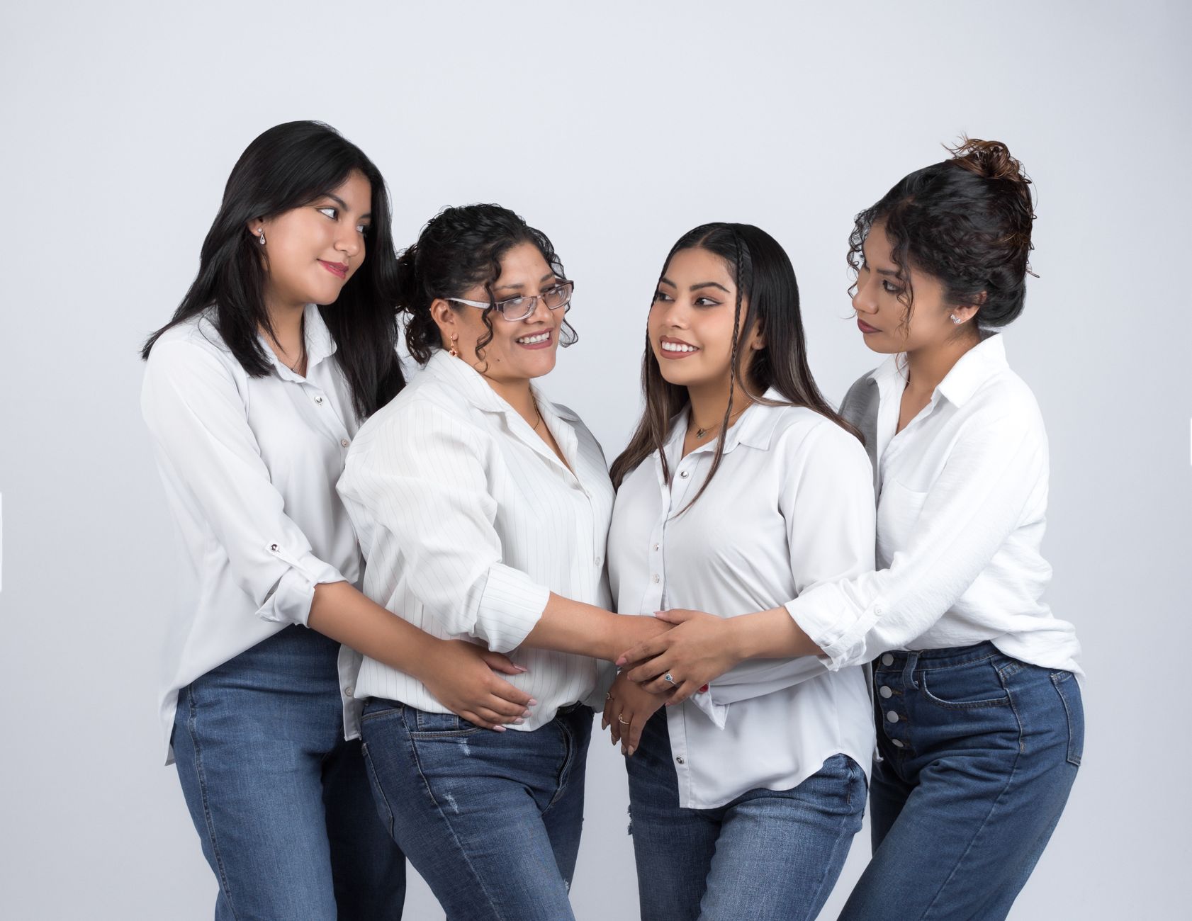 group of women in white shirts and jeans smiling